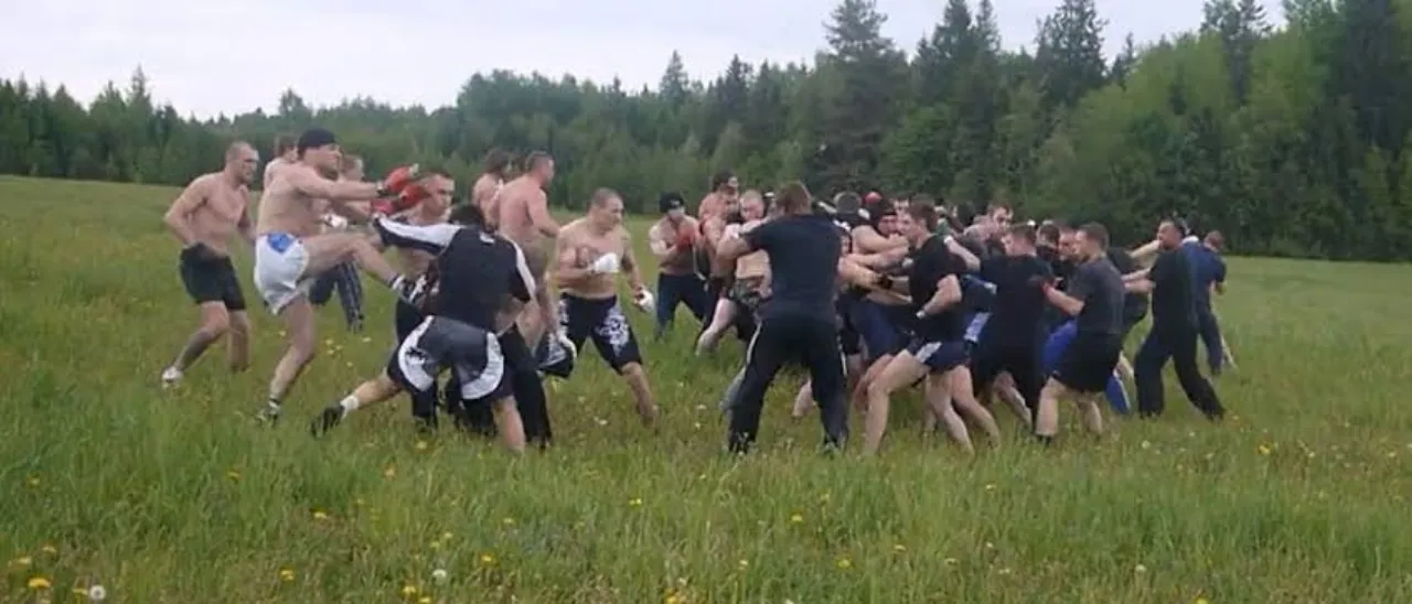 Two groups of men close on each other in a meadow at the edge of a wood — a prearranged fan fight.