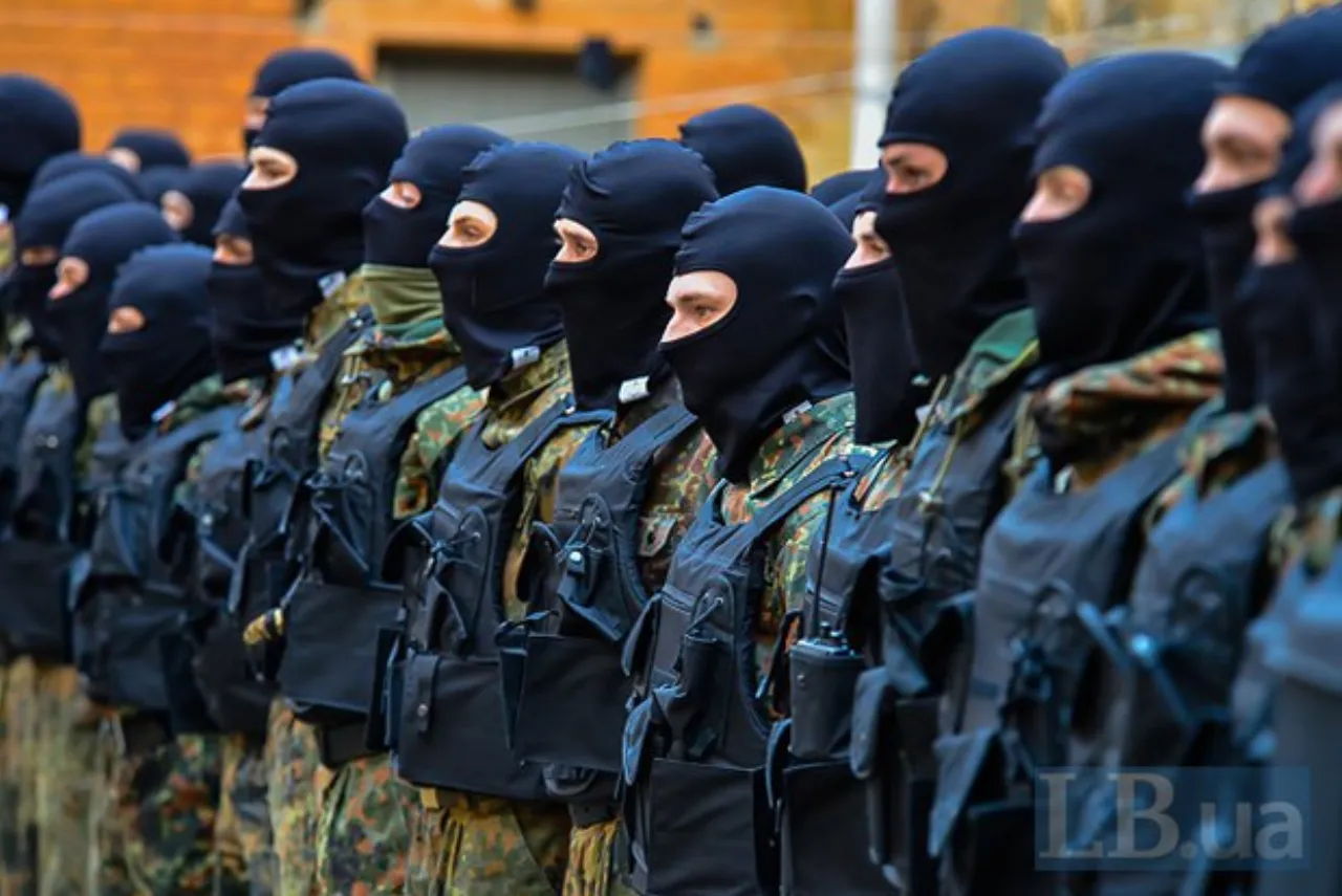 A line of men in black balaclavas and tactical vests standing in close formation.