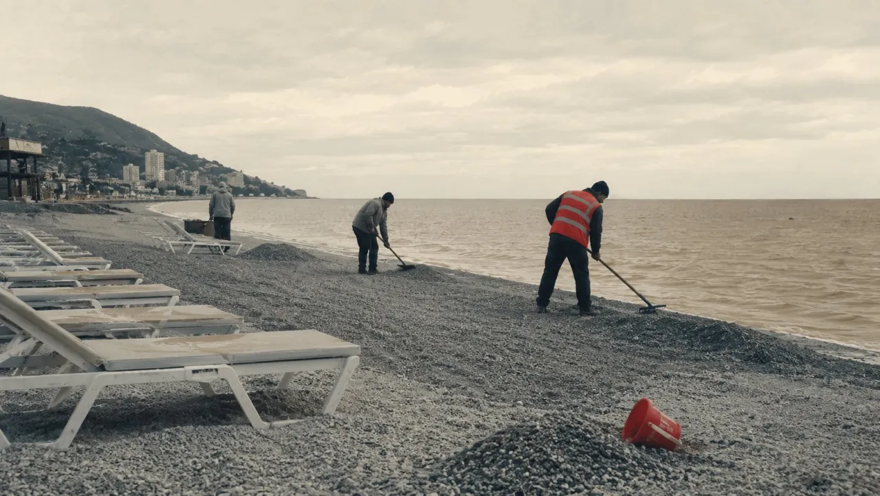 Workers in high-visibility vests rake grey sand beside a row of empty sunbeds.